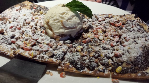 Reeses Peezza flat bread shell topped with chocolate ganache, peanut butter cups, reeses crumbs, peanut butter gelato
